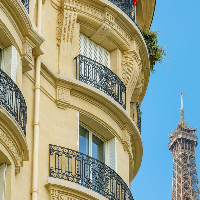 Immeuble haussmannien à Paris avec persiennes blanches, balcons en fer forgé et vue sur la Tour Eiffel – RENOSTYLES Patrimoine.